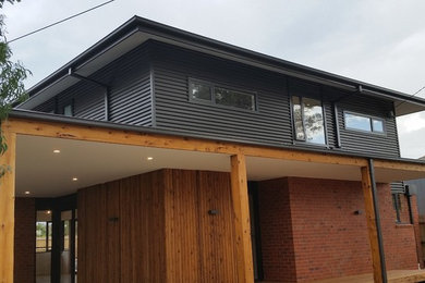 Photo of a black and large industrial two floor detached house in Melbourne with a metal roof, metal cladding and a hip roof.