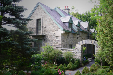 Example of a classic gray two-story stone gable roof design in Montreal