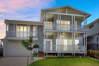 Cette photo montre une grande façade de maison grise tendance en bois à un étage avec un toit à quatre pans et un toit en métal.