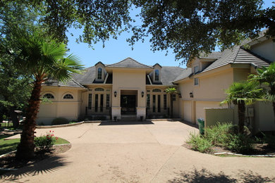 Tuscan beige two-story stucco house exterior photo in Austin with a hip roof and a tile roof