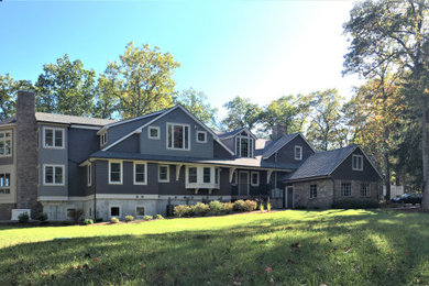 Modelo de fachada de casa gris de estilo americano grande de tres plantas con revestimientos combinados, tejado a dos aguas y tejado de teja de madera