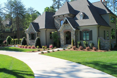 Example of a large transitional gray two-story stone house exterior design in Charlotte with a hip roof and a shingle roof