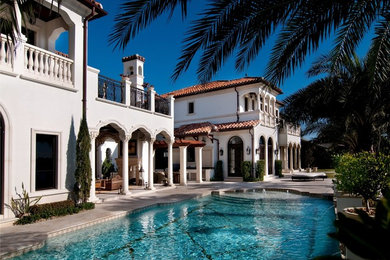 Example of a huge tuscan beige two-story stone exterior home design in Miami