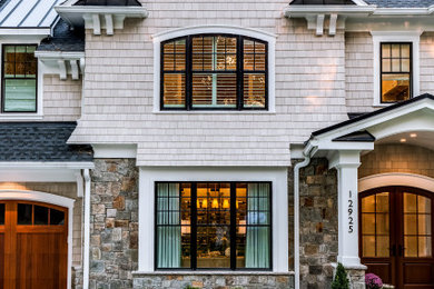 Modelo de fachada de casa beige de estilo americano extra grande de tres plantas con revestimientos combinados, tejado a cuatro aguas y tejado de varios materiales