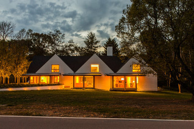 Diseño de fachada de casa blanca actual de tamaño medio de dos plantas con tejado a dos aguas y tejado de teja de madera