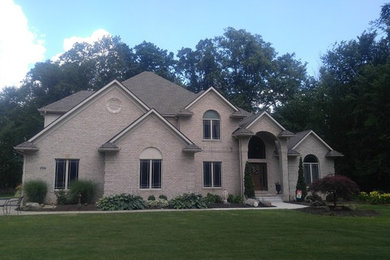 Imagen de fachada de casa beige contemporánea de tamaño medio de dos plantas con revestimientos combinados, tejado a dos aguas y tejado de teja de madera
