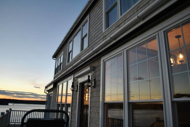 Aménagement d'une façade de maison grise en bois à un étage avec un toit à deux pans.