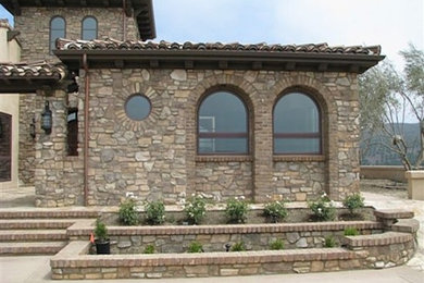 Aménagement d'une façade de maison beige en pierre de taille moyenne et à un étage.