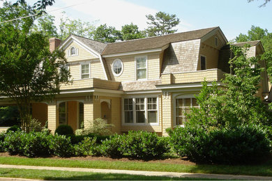 Inspiration for a large yellow two-story wood exterior home remodel in Raleigh with a clipped gable roof