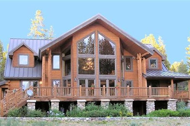 Ejemplo de fachada de casa marrón rústica grande de dos plantas con revestimiento de madera, tejado a cuatro aguas y tejado de metal