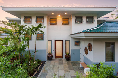 Mid-sized white two-story stucco house exterior photo in Hawaii with a hip roof and a tile roof