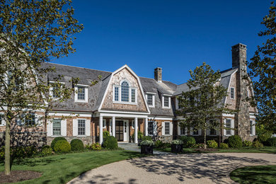 Example of a large classic multicolored two-story house exterior design in New York with a gambrel roof and a shingle roof