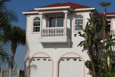 Inspiration for a large and white world-inspired two floor render house exterior in Tampa with a hip roof.