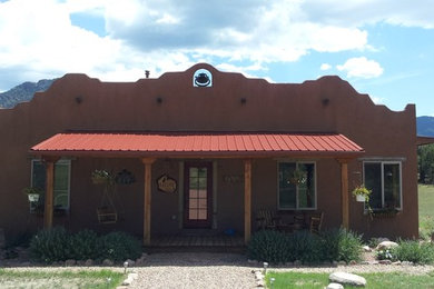 Ejemplo de fachada marrón de estilo americano de tamaño medio de una planta con revestimiento de adobe y tejado plano