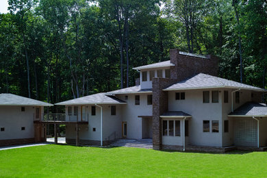 Modelo de fachada gris contemporánea grande de tres plantas con revestimientos combinados y tejado a cuatro aguas