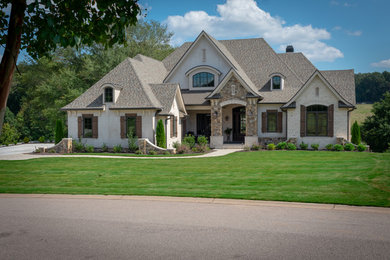 Large transitional beige two-story stucco house exterior idea in Other with a hip roof and a shingle roof