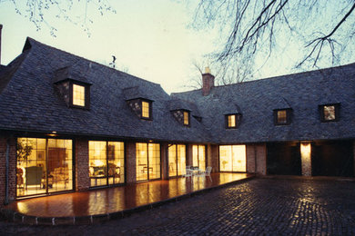 Cette photo montre une grande façade de maison beige chic en brique à un étage avec un toit à quatre pans et un toit en shingle.