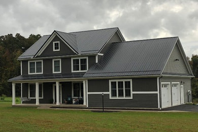 Exemple d'une façade de maison marron nature de taille moyenne et à un étage avec un revêtement en vinyle, un toit à deux pans et un toit en métal.