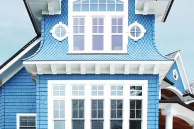 Imagen de fachada de casa azul marinera grande de tres plantas con revestimientos combinados