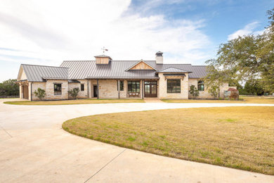 Inspiration for a farmhouse beige one-story stone exterior home remodel in Austin with a metal roof