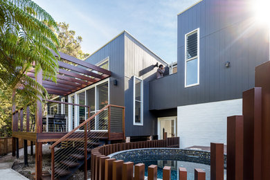 Идея дизайна: двухэтажный, черный частный загородный дом среднего размера в современном стиле с плоской крышей и металлической крышей