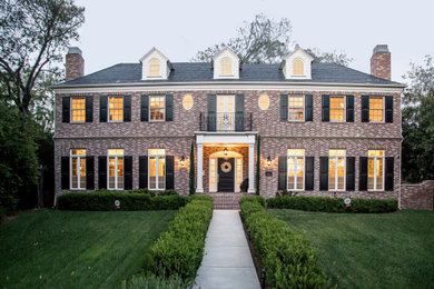 Elegant red two-story brick house exterior photo in Los Angeles with a hip roof and a shingle roof