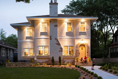 Example of a large transitional beige two-story stucco exterior home design in Minneapolis with a hip roof