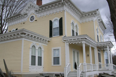Photo of a yellow victorian house exterior in Boston with three floors, wood cladding and a pitched roof.