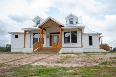 Imagen de fachada de casa blanca campestre de una planta con revestimiento de aglomerado de cemento y tejado de metal