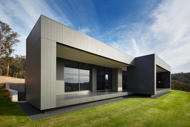 Foto på ett funkis grått hus, med allt i ett plan, fiberplattor i betong och platt tak