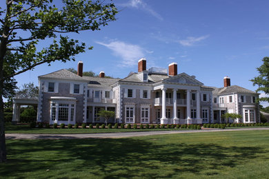 Foto della villa ampia beige classica a tre piani con rivestimenti misti, tetto a padiglione e copertura a scandole