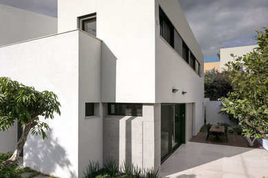 Пример оригинального дизайна: двухэтажный, белый дом среднего размера в стиле модернизм с облицовкой из цементной штукатурки и плоской крышей