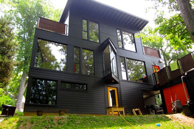 This is an example of a black modern detached house in Louisville with three floors.