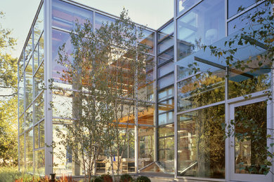Cette image montre une façade de maison design en verre à un étage avec un toit plat.