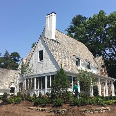 Inspiration for a large timeless white three-story stucco exterior home remodel in New York with a mixed material roof