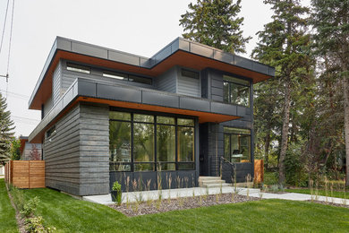 Modelo de fachada de casa negra actual de dos plantas con revestimientos combinados y tejado plano