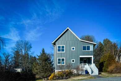 Imagen de fachada de casa gris de tamaño medio de dos plantas con revestimiento de aglomerado de cemento, tejado a dos aguas y tejado de teja de madera