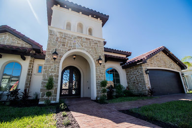 Example of a mid-sized classic beige one-story stucco exterior home design in Other with a tile roof