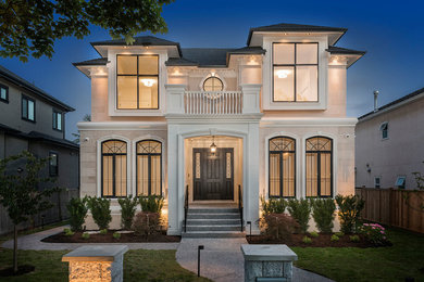 Example of a large french country white two-story stone house exterior design in Vancouver with a hip roof and a shingle roof