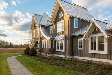Imagen de fachada de casa marrón de estilo de casa de campo de tamaño medio de dos plantas con revestimiento de madera, tejado a dos aguas y tejado de metal