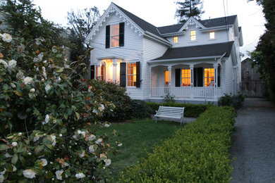 Foto della facciata di una casa grande bianca vittoriana a due piani con rivestimento in legno e tetto a capanna
