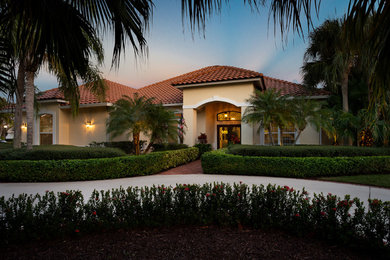 Example of a large tuscan yellow one-story stucco house exterior design in Other with a hip roof and a tile roof