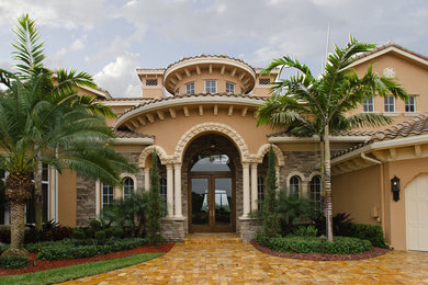 Immagine della facciata di una casa ampia beige mediterranea a tre piani con rivestimenti misti