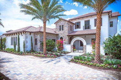 Inspiration for a huge mediterranean white two-story stone exterior home remodel in Miami with a shingle roof