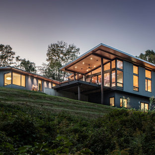 Modelo de fachada de casa azul, contemporánea, de tamaño medio, de dos plantas, con revestimiento de metal, tejado plano y tejado de metal