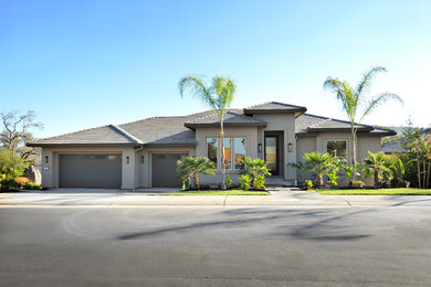 Diseño de fachada de casa gris contemporánea de tamaño medio a niveles con revestimiento de estuco, tejado a cuatro aguas y tejado de teja de barro