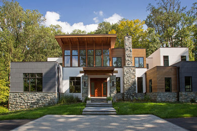 Ejemplo de fachada de casa moderna de tres plantas con revestimiento de piedra y tejado plano