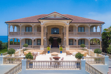 Imagen de fachada de casa beige mediterránea grande con tejado a cuatro aguas y tejado de teja de barro