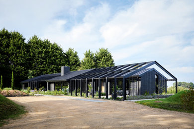 Diseño de fachada de casa negra actual grande de una planta con revestimiento de ladrillo, tejado de metal y tejado a dos aguas