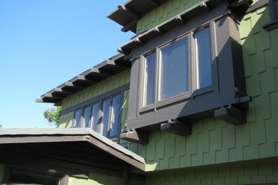 Diseño de fachada de casa verde de estilo americano grande de dos plantas con revestimiento de madera, tejado a dos aguas y tejado de teja de madera